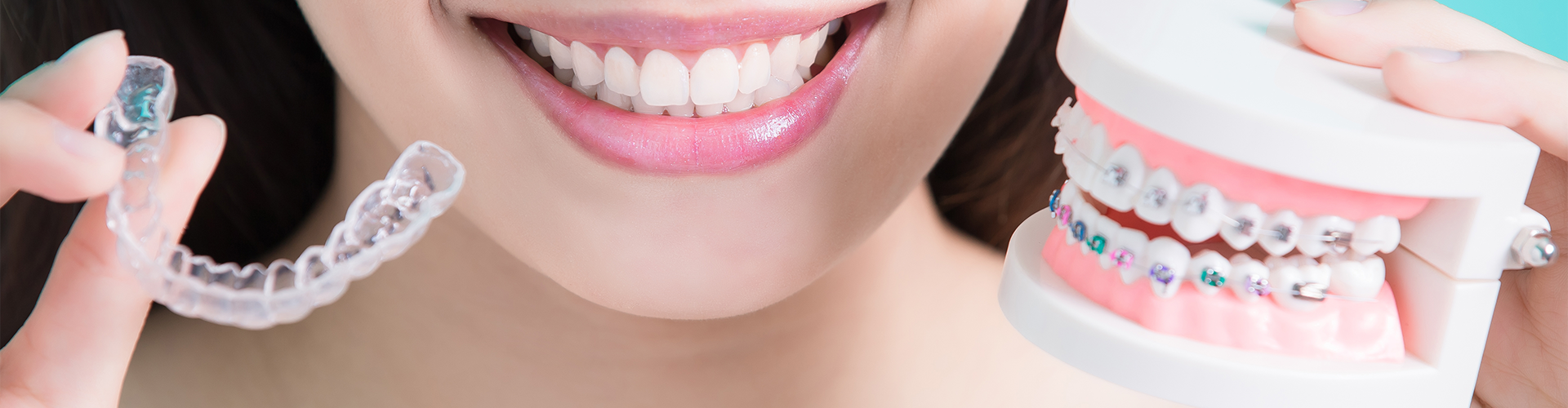 woman holding braces in one hand and clear aligners in the other